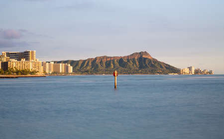 Panorama of the skyline of Honolulu and Waikiki from Ala Moana park as the sun sets and illuminates the facades of the hotels and apartmentsの写真素材