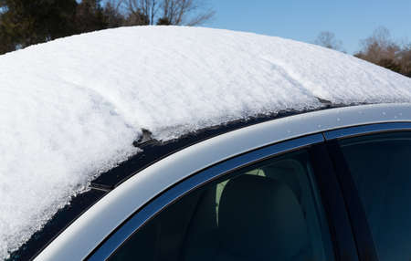Deep snow piled high on top of white four door sedan car in rural settingの写真素材