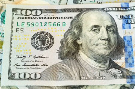 New design of US currency one hundred dollar bills laid out on table with focus on Ben Franklin...