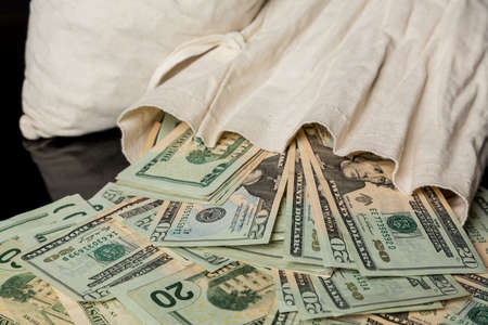 Thousands of US dollars pouring out of a cloth money bag の写真素材