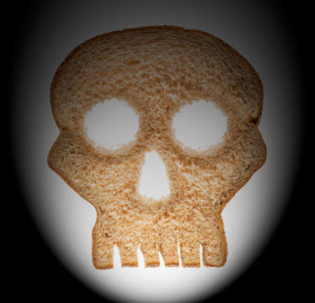 Skull shaped piece of bread cut from whole wheat loaf to illustrate danger from gluten in wheat...