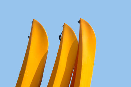Three yellow prows of canoes or kayak with clipping path to allow easy isolation from blue sky behind the boatsの写真素材