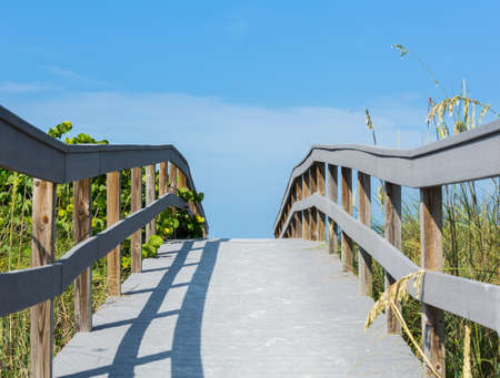 Wooden boardwalk to ocean amond sea oats on Sunset Beach at southern tip of Treasure Island Florida on Gulf of Mexicoの写真素材