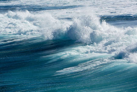 Frozen motion of large wave or breaker approaching shore and short shutter speed freezing the water into dropletsの写真素材