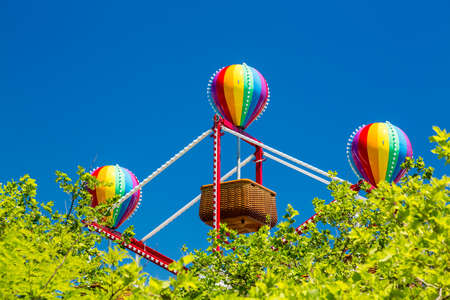 Colorful lighted balloon shapes above baskets on childrens fairground ferris wheelの写真素材