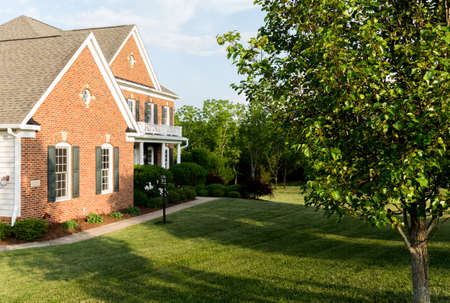 Front of home and garage of large single family modern US house with landscaped gardens and lawn on a warm sunny summers dayの写真素材