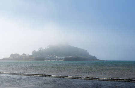 Time coming in to cover the causeway in front of mist or fog covered island of St Michaels Mount near Marazion, Cornwall, England UKの写真素材