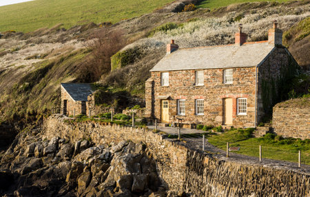 View of stone cottage and hillside in late evening sunlight in Port Quin, Cornwall, England, UKのeditorial素材