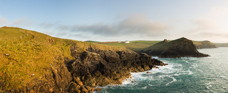 Doyden Castle on headland and whitewashed house on wide panorama of coastline at Port Quin, Cornwall, England, United Kingdomのeditorial素材