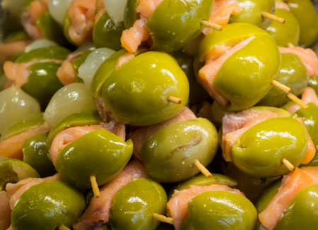 Green olives and salmon on plate of hors-d'oeuvres or entradas in food counter in Spanish market in Madridの写真素材
