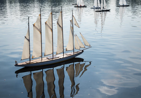 Model yacht with many sailes races across Round Pond in Kensington Gardens, London, England