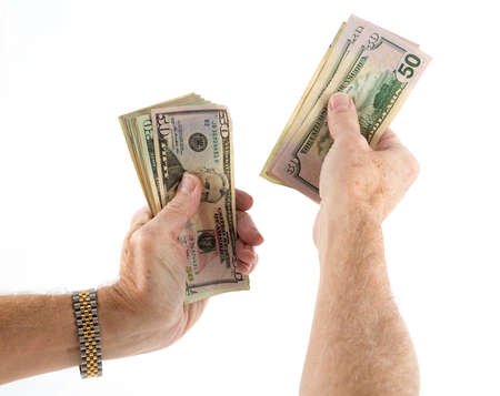 Stack of fifty and twenty US dollar bills being held by pair of senior caucasian hands as though...