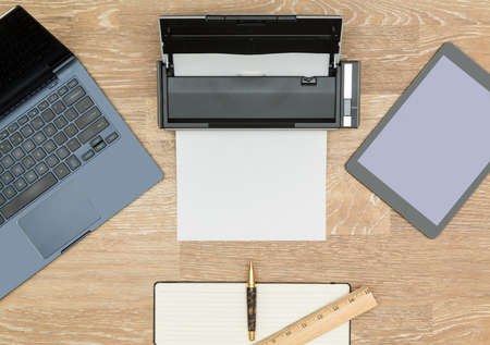 Tidy organized desk top with laptop, tablet, scanner and notebook with pen on an oak wooden table for designer workspaceの写真素材