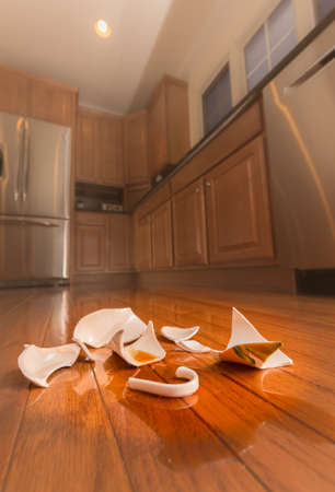 Concept of domestic disturbance at home with broken coffee cup on floor of modern kitchenの写真素材