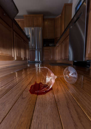 Concept of domestic disturbance at home with broken wine glass on floor of modern kitchenの写真素材