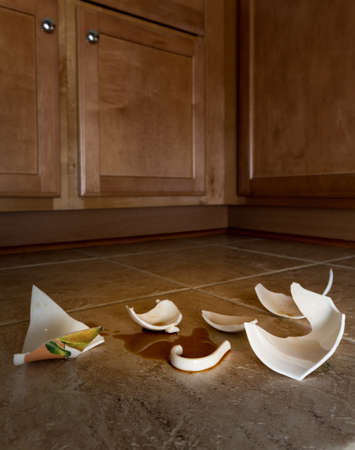 Concept of domestic disturbance at home with broken coffee cup on floor of modern kitchen