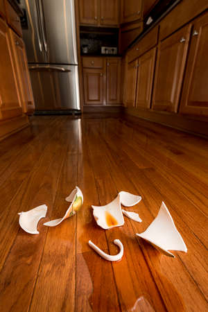 Concept of domestic disturbance at home with broken coffee cup on floor of modern kitchen