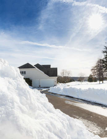 Piles of snow after the driveway to a modern single family house has been cleared after blizzard and snow driftsの写真素材