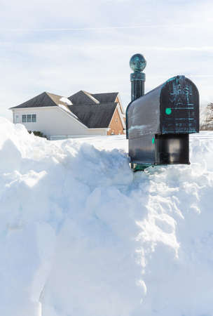 Piles of snow bury the mail box of a modern single family house after blizzard and snow driftsの写真素材