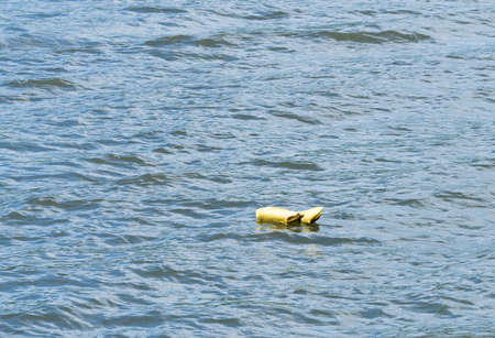 Yellow life preserver abandoned and floating down the river with nobody thereの写真素材
