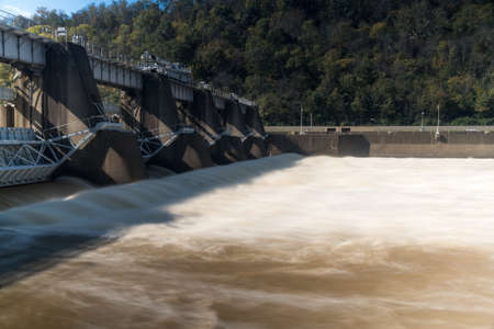 Blurred motion water pours from sluice gates in concrete lock and dam on the River Monongahela in Morgantown West Virginiaの写真素材