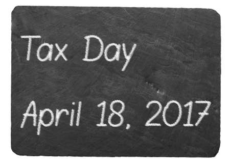 Tax submission day text message written in chalk on a chalky natural slate blackboard isolated against white background with copy spaceの写真素材