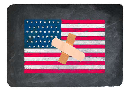 Time for healing concept with adhesive bandage on USA Flag drawn in chalk on a chalky natural slate blackboardの写真素材