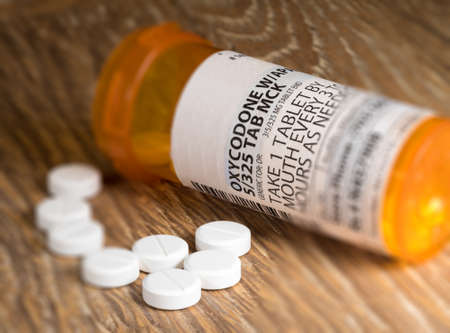 Tiltshift effect of prescription bottle for Oxycodone tablets and pills on wooden table for opioid epidemic illustrationの写真素材