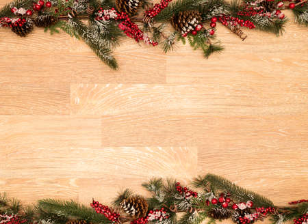Christmas or Xmas Holiday background on old plank wood with fir branches, red berries, pine cones and snowの写真素材