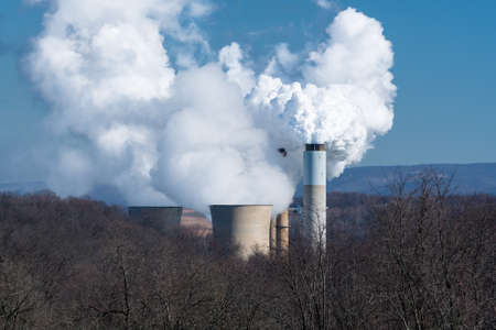 Smoke and steam billowing from chimneys and cooling towers of coal powered power station in West Virginiaの写真素材