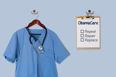 Blue medical scrubs uniform shirt hanging on a hanger with stethoscope with Obamacare options on clipboardの写真素材