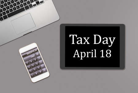 Overhead clean desk for laptop, smartphone and tablet computer with message for tax day 2017 as April 18の写真素材