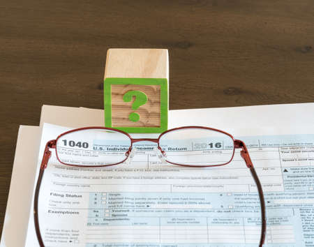 Question mark wooden block illustrating problems or issues in completing US IRS tax formの写真素材