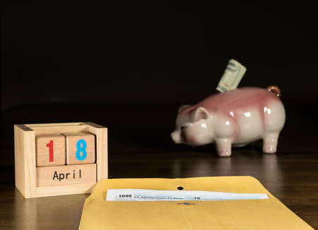 Wooden letters in calendar with Form 1040 income tax for 2016 showing tax day for filing is April 18...