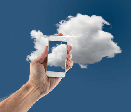 Concept image for cloud computing and online applications showing modern smartphone held in male hand up to skyの写真素材