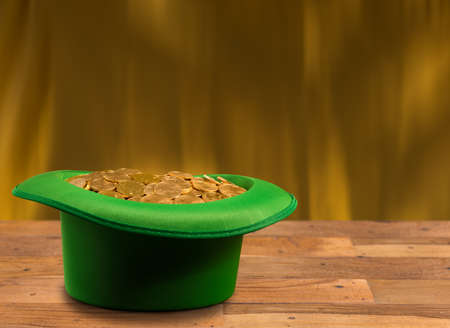Treasure of pure gold coins inside a green velvet hat on wooden table to celebrate luck on St Patricks Day of March 17thの写真素材