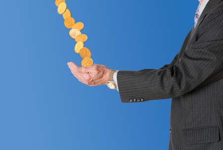 Senior caucasian businessman or executive isolated against white background. Subject is in profile and is collecting gold coins falling from blue skyの写真素材