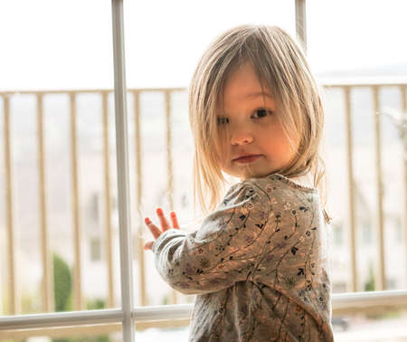 Young caucasian female toddler looking seriously at the camera with strong backlighting