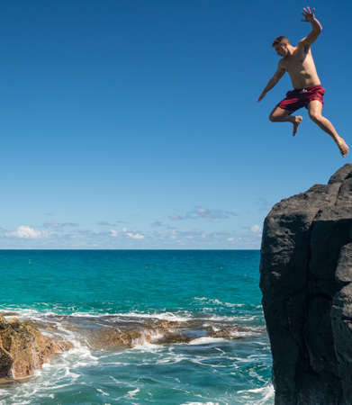 Dangerous leap into warm blue ocean off rocks at Lumahai Beach on Hawaiian island of Kauaiの写真素材