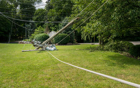 Broken snapped wooden power line post with electrical components on the ground after a stormの写真素材