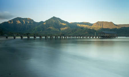 Sunrise lights the dawn sky above Hanalei Bay and pier with the Na Pali coast in the background near Hanalei, Kauai, Hawaiiの写真素材