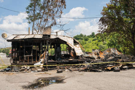 Burnt or burned out ruins of wooden framed home with metal roofの写真素材