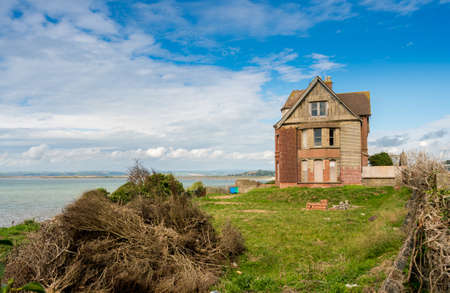 Sea erosion of cliffs in front of derelict house near Westward Ho in Devon, Englandの写真素材