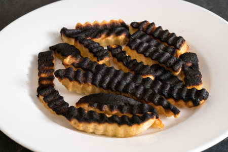 Burnt and ruined french fries or chips after leaving under the grill for too long and charring themの写真素材