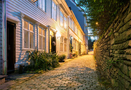 Narrow cobbestone Nedre Strangehagen Street at dusk in the old town of Bergen in Norwayの写真素材
