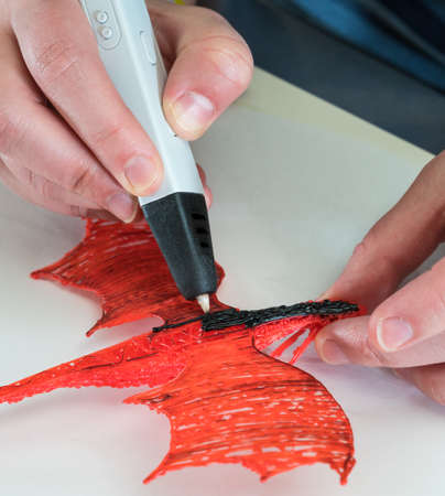 3D printing pen working by melting ABS plastic to create a model of a dragon