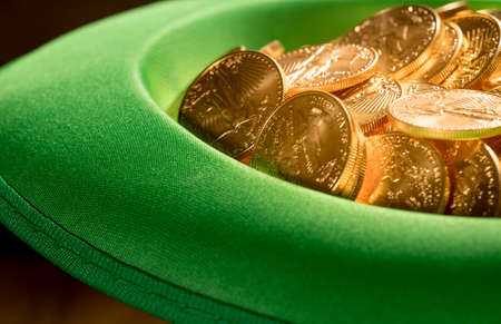 Treasure of pure gold eagle coins inside the rim of a green velvet hat to celebrate luck on St...