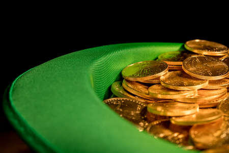Treasure of pure gold eagle coins inside the rim of a green velvet hat to celebrate luck on St Patricks Day of March 17thの写真素材