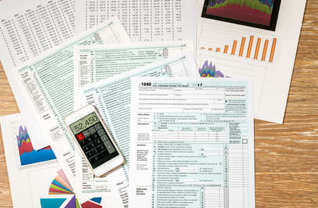 From above view of USA tax form 1040 for 2017 with charts and calculations on wooden desk