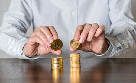 Senior man holding gold coins alongside stack of bitcoins to illustrate investment choice